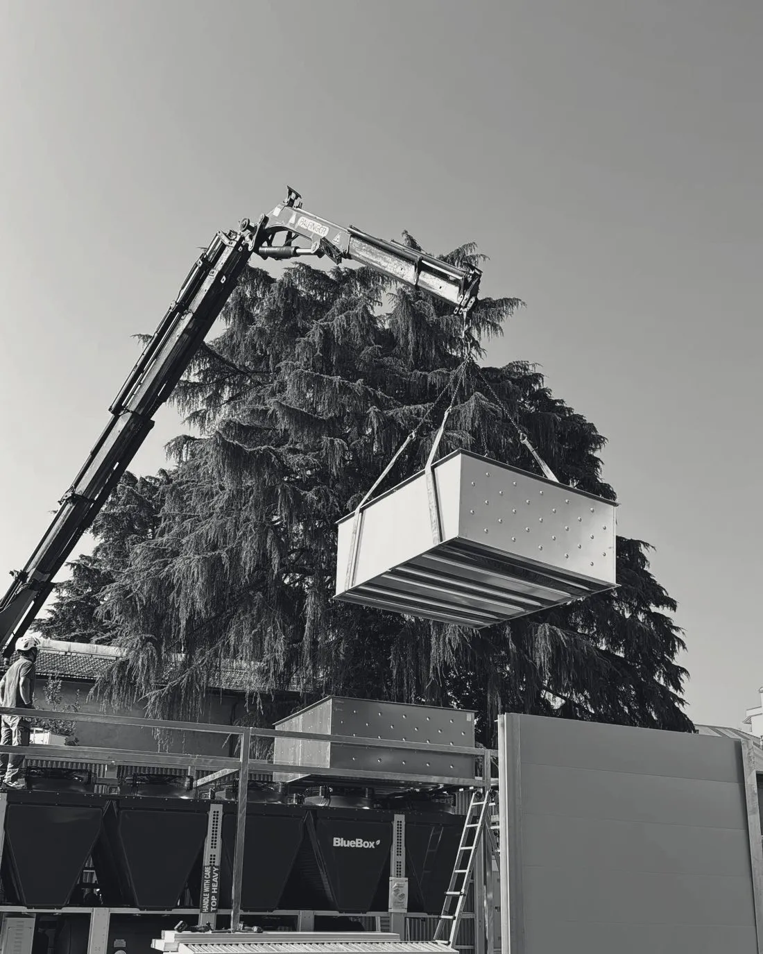 A crane lifting an enclosure module into place on site